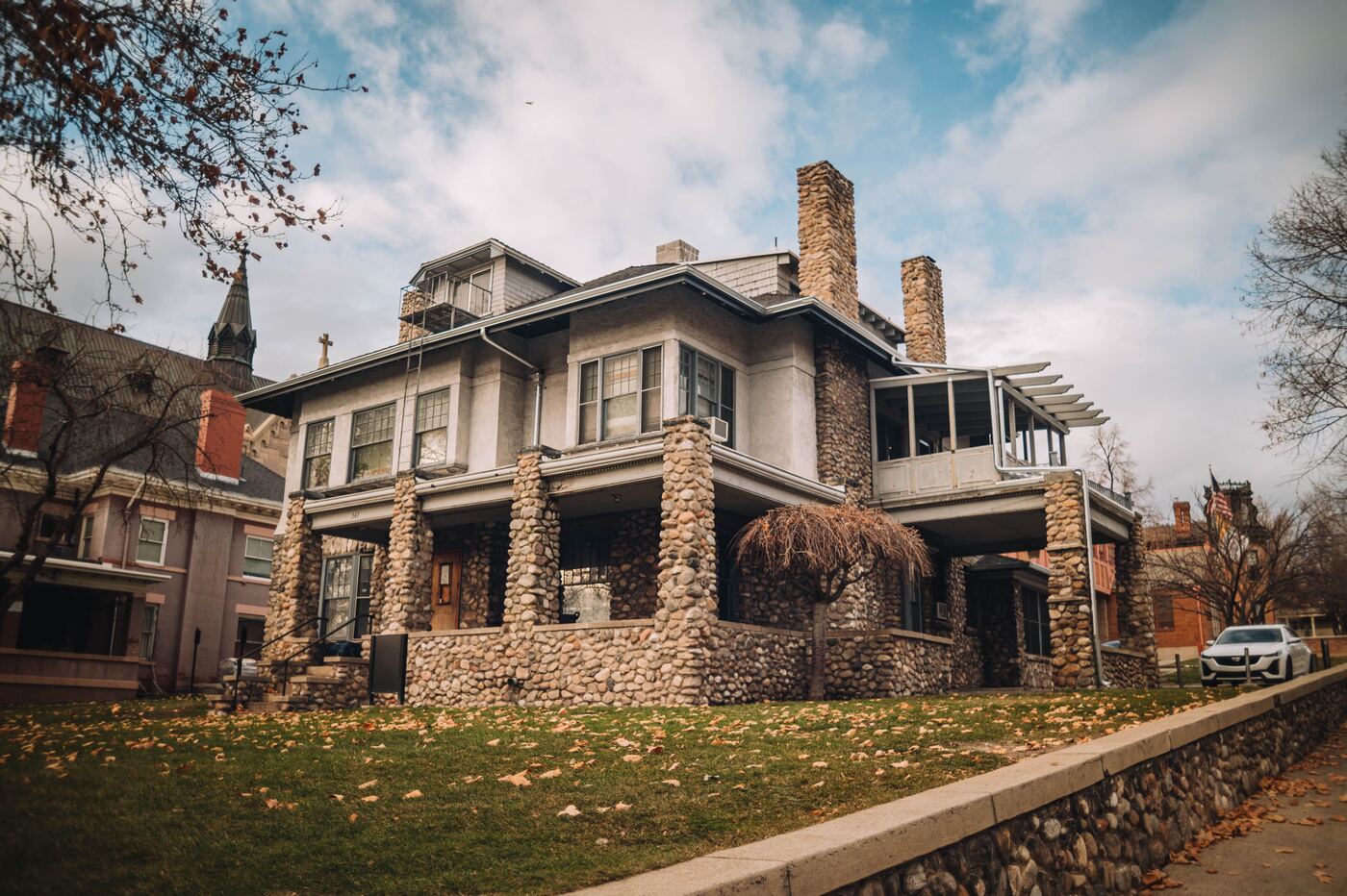 An older two-story home with a stone porch and river-rock foundation