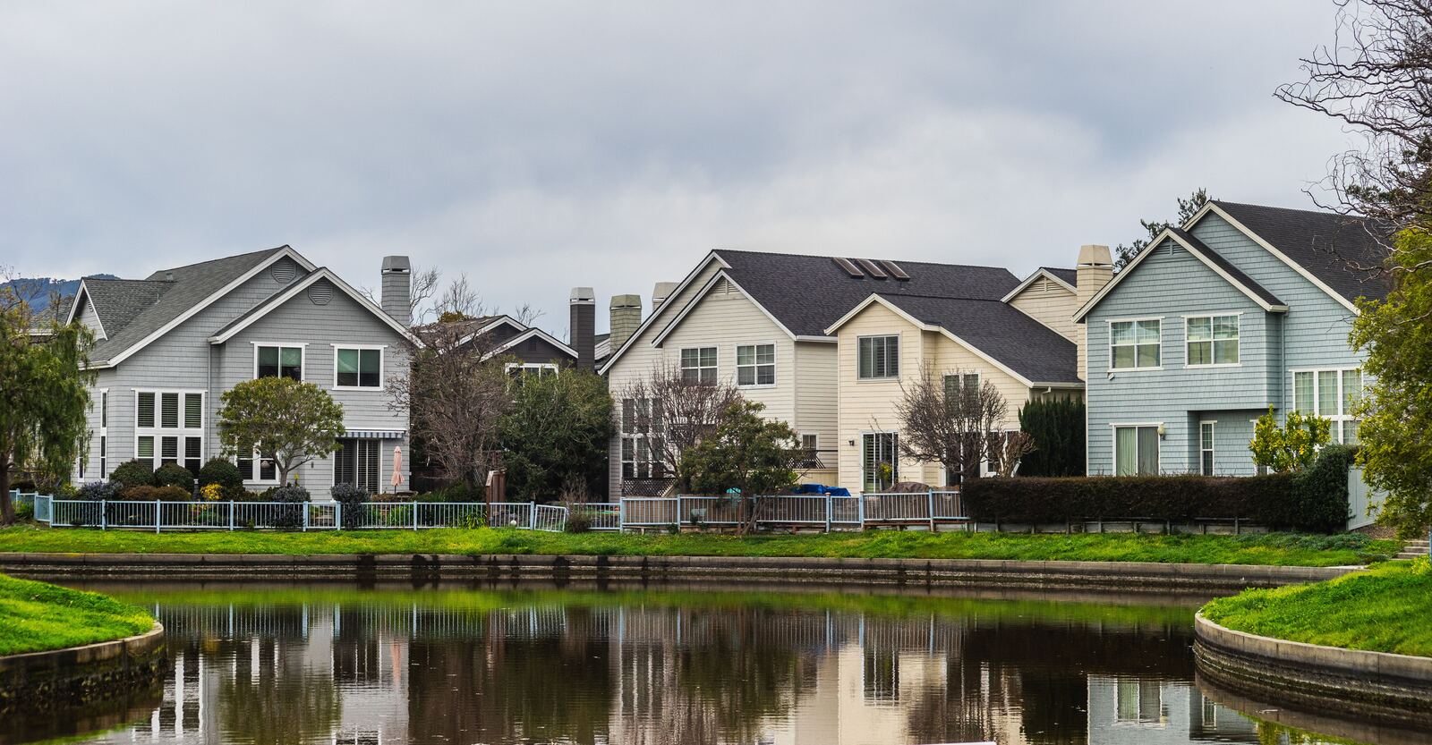 A row of newer two-story homes along a pond and walking path
